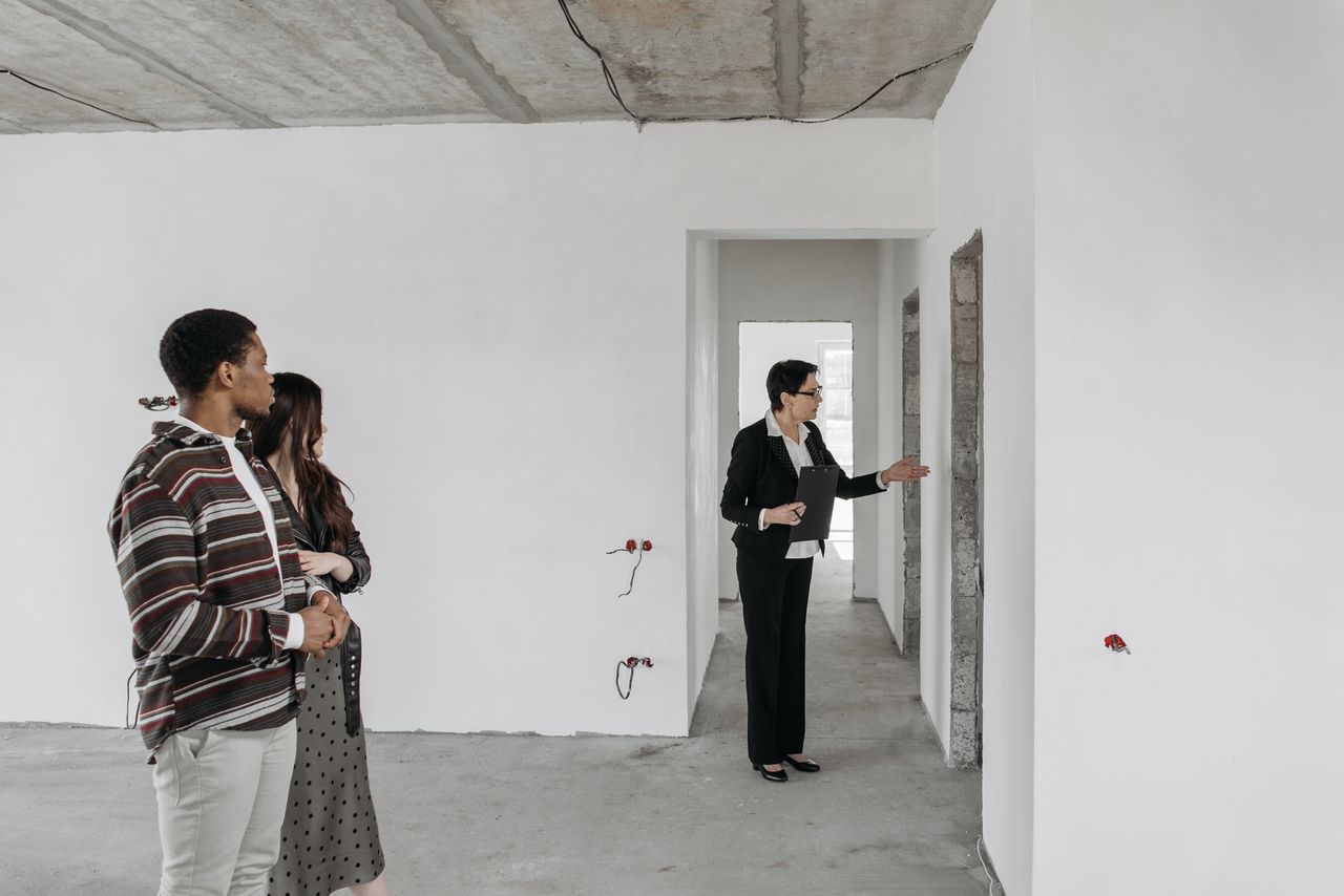 The Art of Drawing Readers In: Your attractive post title goes here A couple explores an unfinished apartment with a real estate agent, considering property purchase options.